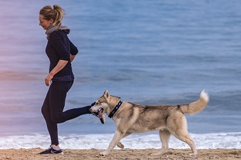 a woman running on a beach with her dog